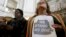 FILE - A woman holds a sign while listening to speakers at a meeting at City Hall in San Francisco to reaffirm the city's commitment to being a sanctuary city, Nov. 14, 2016.