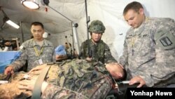 16일 서울 특수전사령부에서 열린 사상 첫 한·미 연합 군종 야외기동훈련에 참가한 군종장교가 야전수술시 군종조치훈련에서 부상자 머리에 손을 올리고 기도하고 있다.