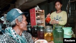 FILE PHOTO - A Cambodian customer waits for a glass of the popular local rice wine at a Phnom Penh street stall. (REUTERS)
