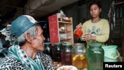FILE PHOTO - A Cambodian customer waits for a glass of the popular local rice wine at a Phnom Penh street stall. (REUTERS)
