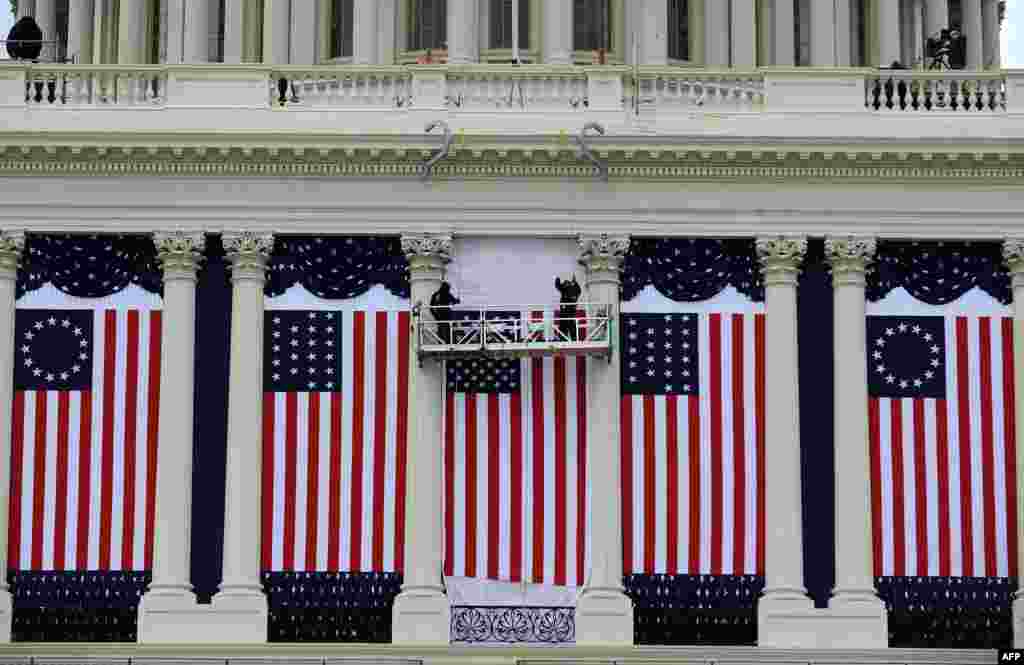 Dua pekerja membetulkan bendera-bendera AS di gedung Capitol di tengah persiapan upacara pelantikan kedua Presiden Barack Obama di Washington, D.C. (17/1)
