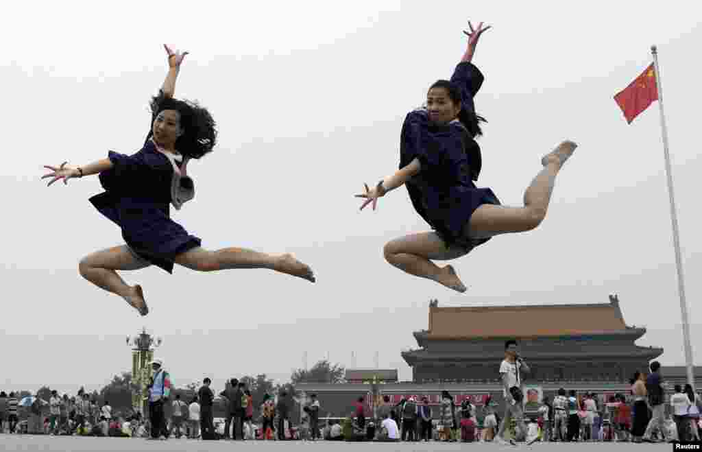 Dua orang yang baru lulus melompat ketika foto mereka diambil di depan GerbangTiananmen dan potret raksasa mending pemimpin China Mao Zedong, di alun-alun Tiananmen di Beijing, China, 19 Juni 2014. &nbsp;