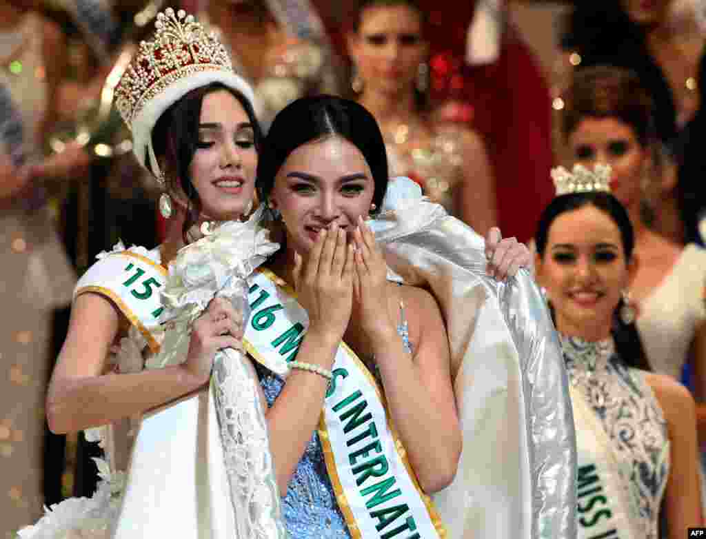 Kylie Verzosa dari Filipina (tengah) menerima gaun kemenangan sebagai Miss International 2015 dari pemenang sebelumnya, Edymar Martinez dari Venezuela (kiri) pada final lomba kecantikan pageant di Tokyo, Jepang.