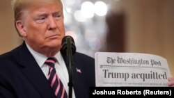 特朗普在白宫东室展示《特朗普被判无罪》的《华盛顿邮报》大字标题。(2020年2月6日)