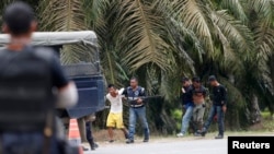 Polisi Malaysia menahan dua orang yang keluar dari Tanjung Labian, sebuah desa dekat Kampung Tanduo, Rabu (6/3). Tentara Malaysia bentrok dengan kelompok bersenjata Filipina di wilayah tersebut, Selasa (5/3). 