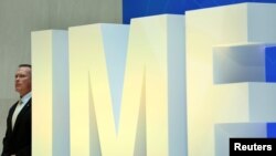FILE - A security personnel stands next to International Monetary Fund logo at IMF headquarters in Washington, April 19, 2017. 