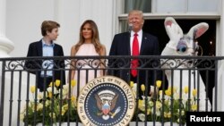 Le président américain Donald Trump aux côtés de la Première Dame Melania et de leur fils Barron, en présence d'un acteur revêtu du costume d'un lapin géant à l'occasion de la traditionnelle chasse aux œufs de Pâques de la Maison Blanche à Washington, le 17 avril 2017.