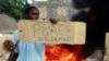 A resident holds a sign as he participates in a protest against the recent attack by gunmen in the coastal Kenyan town of Mpeketoni, June 17, 2014. 