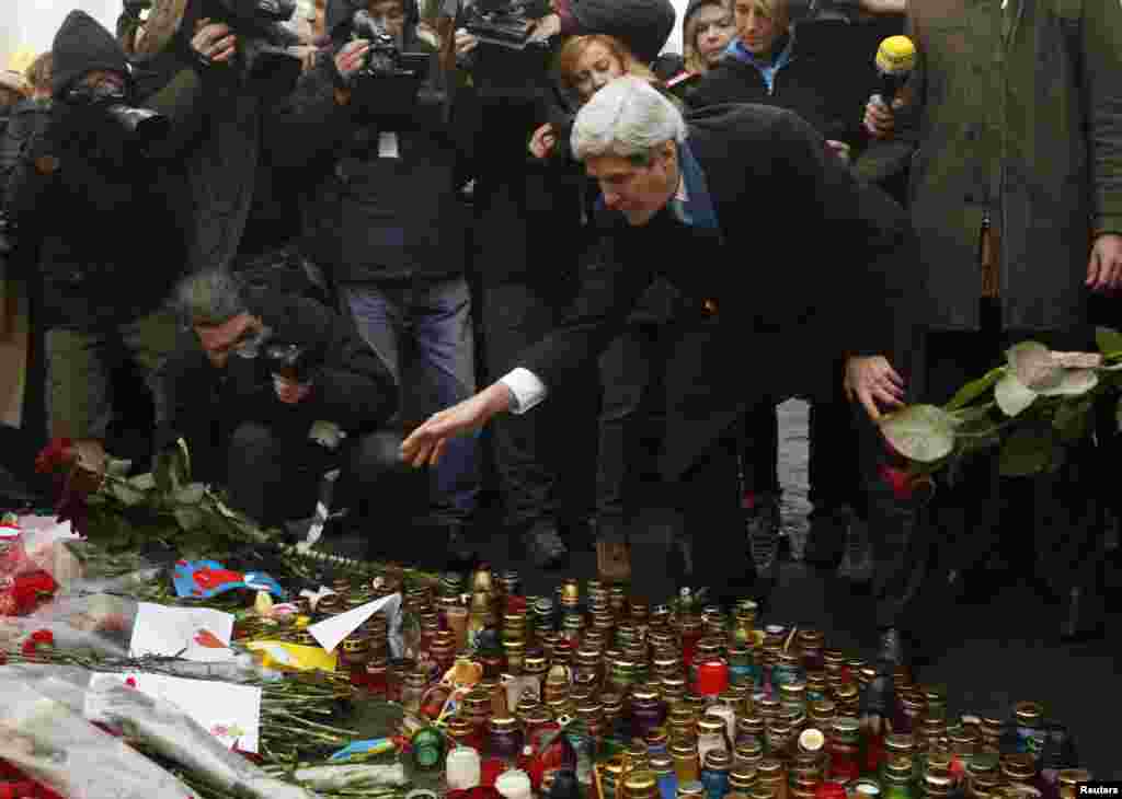 Menteri Luar Negeri AS John Kerry menaruh bunga mawar di atas tempat penghormatan korban tewas dalam bentrokan antara polisi dan demonstran di Kyiv, Ukraina (4/3). (Reuters/Kevin Lamarque)