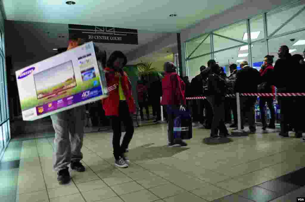 2012年11月22日，在维吉尼亚州阿灵顿，购物者抱着电视离开，其他人则蜂拥进入商店。 (D. Manis/VOA) 