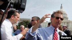 两名共和党籍参议员特德•克鲁兹（左）和兰德•保罗（右）赶到国会山西侧草坪参加反奥巴马医保集会时对媒体讲话。（2013年9月10日）