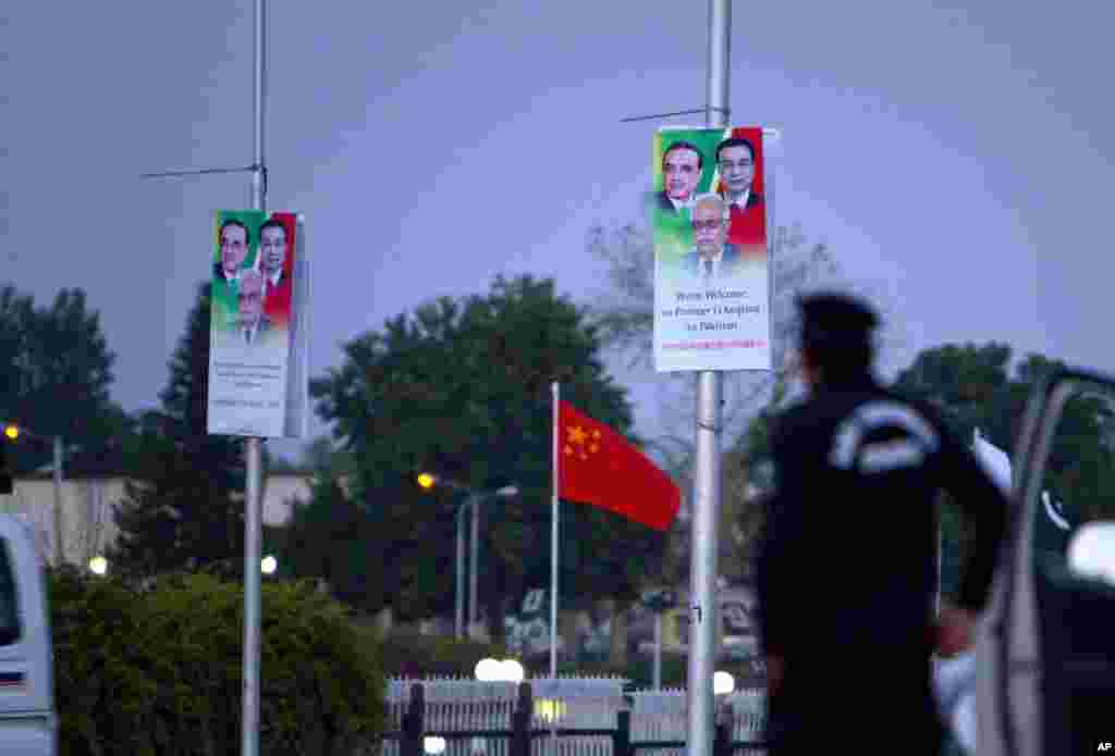 A police officer stands guard next to billboards welcoming Chinese premier Li Keqiang hung on poles near the presidency in Islamabad, Pakistan.
