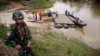 FILE - A soldier stands guard on the Thai side of the river as people prepare to cross into Malaysia in Sungai Kolok in southern Narathiwat province, March 8, 2013. 