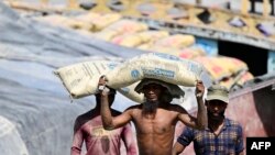 ঢাকার কাছে বুরিগঙ্গার তীরে শ্রমিকরা সিমেন্টের বস্তা মালবাহী নৌকা থেকে নামাচ্ছেন। ফটোঃ ২০ এপ্রিল, ২০২৪। 