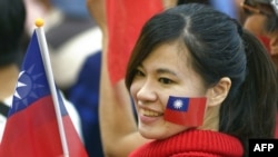 资料照：一名台湾女子脸颊上贴着台湾旗帜并手举台湾旗帜参加集会。