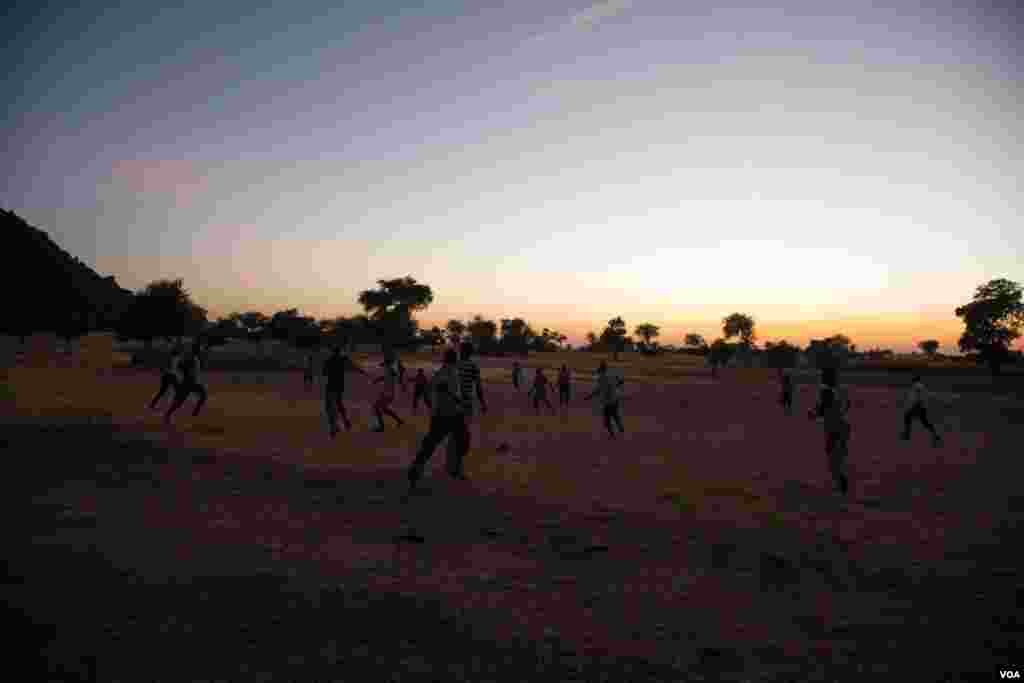 As night falls, a group of boys from the caves come out of hiding and play football in the brief moments of peace before dark. (Adam Bailes/VOA News)