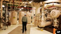FILE - A worker walks past equipment in the turbine building at the Oyster Creek nuclear plant in Lacey Township, N.J., Feb. 25, 2010.