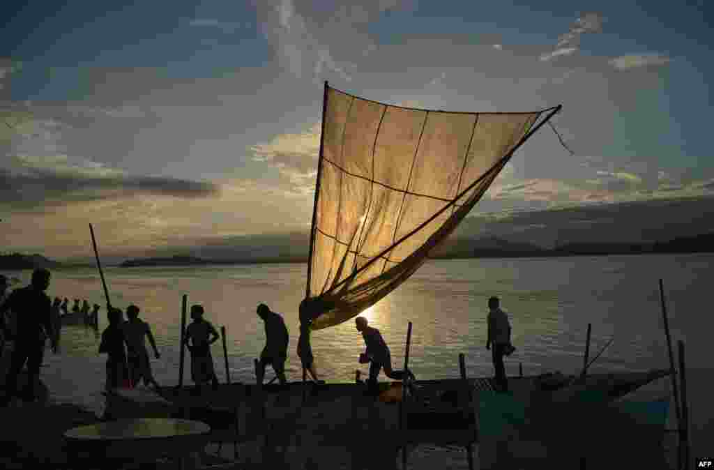 Fishermen load their boat with fish to sell at a market on the banks of the Brahmaputra River at Ujanbazar Ghat in Guwahati, India.
