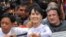 Burma opposition leader Aung San Suu Kyi (C) waves to the crowd as she leaves National League for Democracy (NLD) headquarters after addressing journalists and supporters in Yangon on April 2, 2012.