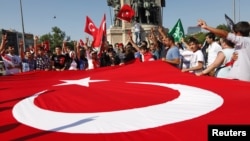 Demonstrators wave a huge national flag as they shout slogans in support of the Turkish military in central Istanbul, June 24, 2012.