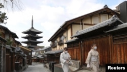 日本京都两名戴着口罩的妇女走过空荡荡的街头。（2021年月13日）