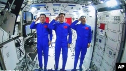Des astronautes chinois, de gauche à droite ; Tang Hongbo, Nie Haisheng et Liu Boming font un salut depuis le module central de la station spatiale chinoise Tianhe lors d'une conversation vidéo avec le président chinois Xi Jinping. (photo/Agence de presse chinoise Xinhua)