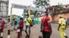 FILE - People, some wearing masks, walk by the entrance to Yaounde General Hospital, in Yaounde, Cameroon, March 6, 2020, amid the coronavirus pandemic. 