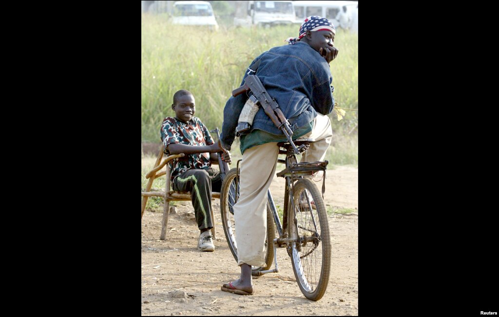 Child soldiers take a rest as they wait for instructions in an ethnic Hema militia camp near Bunia in the Democratic Republic of Congo, June, 2003.
