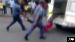 A picture grabbed on an amateur video and released by the South African Daily Sun newspaper shows policemen holding the legs of a Mozambican taxi driver handcuffed to the back of a police van while being dragged by the van in Daveyton, Feb. 28, 20313.