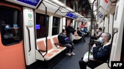 Abiria wakiwa wamevalia maski wakitumia usafiri wa umma kaika Stesheni ya treni ya Atocha, Madrid Aprili 13, 2020, makati wakati baadhi ya makampuni yakiwa tayari kuanza shughuli zao ifikapo mwisho wa amri ya serikali ya wiki mbili kusimamisha shughuli zote ambazo sio muhimu. ( J
