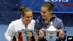 Childhood friends Flavia Pennetta, right, and Roberta Vinci pose with their awards after Pennetta won their women's championship match of the U.S. Open tennis tournament in New York, Sept. 12, 2015.