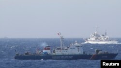 Kapal penjaga pantai China (atas) dan kapal AL Vietnam berpapasan di perairan sengketa di Laut China selatan (14/5). Kedua negara membawa sengketa wilayah kepada Sekjen PBB. 