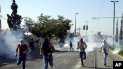 Warga Palestina menghindari gas air mata dalam bentrokan dengan pasukan keamanan Israel saat pemakaman remaja Palestina berusia 16 tahun Mohammed Abu Khdeir di Yerusalem hari Jumat, 4 Juli 2014.