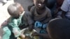 FILE - Children eat on November 13, 2014 in a camp for Nigerian refugees in Minawao, in the extreme north-west of Cameroon. 
