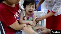 FILE - A child reacts after receiving a measles-rubella vaccination in Yangon, Myanmar, Nov. 26, 2019. 