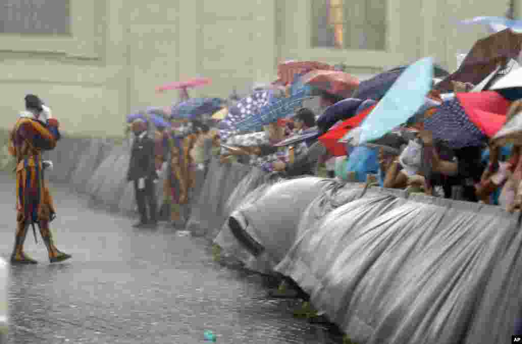 មនុស្ស​ម្នា​ព្យាយាម​ជ្រក​ភ្លៀង​​ពេល​ភ្លៀងធ្លាក់​ខ្លាំង​នៅ​អំឡុងពេល​ការ​ជួប​មហាជន​របស់​សម្តេច​ប៉ាប Francis នៅបូរី​វ៉ាទីកង់។&nbsp;