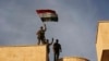 Iraq's elite counterterrorism force soldiers raise an Iraqi flag over the main church in Bartella, Iraq, Oct. 21, 2016.