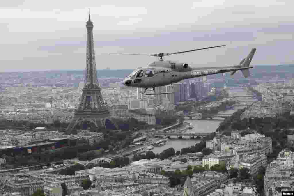 Helikopter angkatan darat Perancis terbang melewati menara Eiffel saat menuju parade Hari Bastille di Paris (14/7).&nbsp;(Reuters/Philippe Wojazer)