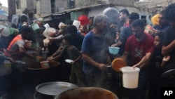 资料照片：在以色列轰炸加沙地带期间，巴勒斯坦人在拉法排队领取食物。(2023年11月13日)