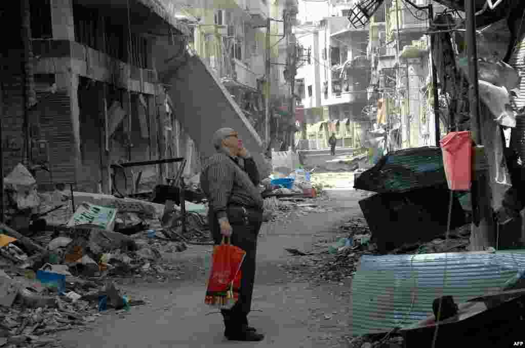 Seorang penduduk Suriah di Homs menatap bangunan yang rusak setelah kembali ke daerah Christian Hamidiyehdi, kota tua yang terletak di kota pusat Suriah, setelah kelompok pemberontak terakhir meninggalkan kota tua Homs di bawah kesepakatan evakuasi yang memberikan kemenangan simbolis bagi pemerintah . &nbsp;