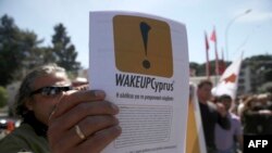 یک شهروند قبرس پلاکاردی را با پیام «از خواب بیدار شو، قبرس» طی تجمعی در روز دوشنبه، ۲۵ مارس ۲۰۱۳ در نیکوزیا، در دست دارد.
