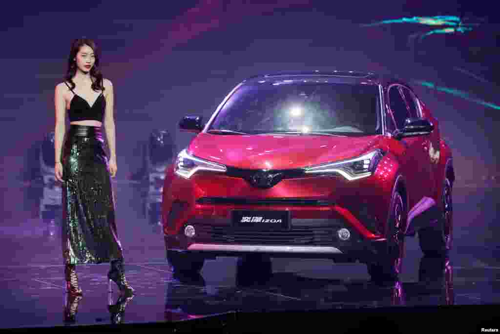 在第十五届北京国际汽车展览会上，车模站在丰田 IZOA 汽车旁边。（2018年4月24日）