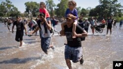 Central American migrants carry children as they run across the Suchiate River from Guatemala to Mexico, near Ciudad Hidalgo, Mexico, Jan. 20, 2020.