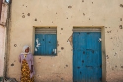 FILE - A woman leans on the wall of a damaged house that was shelled as federal-aligned forces entered the city, in Wukro, north of Mekele, capital of Tigray, March 1, 2021.