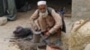 An old man in the bazaar in Lataband Tangi village, Afghanistan, smiled as he looked up from his work. 
