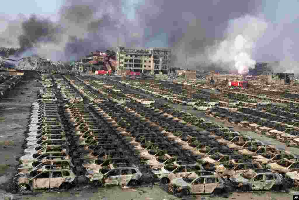 Smoke billows out from the site of an explosion that reduced a parking lot filled with new cars to charred remains at a warehouse in northeastern China&#39;s Tianjin municipality, Aug. 13, 2015. Huge explosions in the warehouse district sent up massive fireballs that turned the night sky into day in the port city, officials and witnesses said.