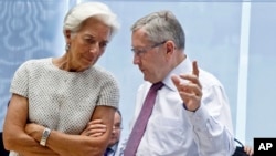 国际货币基金组织常务董事克里斯蒂娜·拉加德(左)正与欧洲金融稳定基金主席克劳斯雷格林(右)在欧盟部长会议上进行交谈(2015年7月11日)。