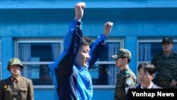 한국 전남 여수 인근 공해상에서 한국 해경에 구조된 북한 선원이 6일 판문점을 통해 북한으로 넘어가기에 앞서 만세를 부르고 있다. 구조된 선원은 3명이고 시신 2구도 송환됐다