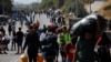FILE - Migrants carry their belongings as they flee a road leading from Moria to the capital of Mytilene, on the northeastern island of Lesbos, Greece, Sept. 17, 2020. 