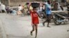 A young boy uses his shirt to dry the water dripping from the bucket onto his face, in Kano, northern Nigeria, Feb. 19, 2019. 